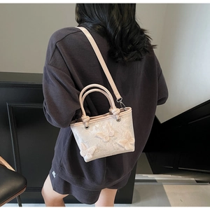 Détail du sac à main en dentelle avec appliques papillon 3D et bandoulière en cuir
