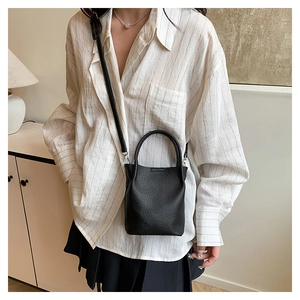 Detail of black lychee grain leather mini bucket bag with top handle and strap
