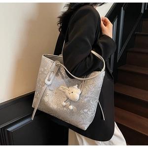 Detail of silver snake-print tote bag with fluffy cloud pendant and metallic texture