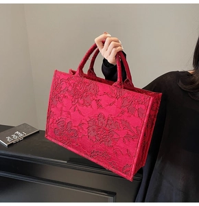 Macro detail of red tote bag with 3D rose jacquard pattern and sturdy carry handle