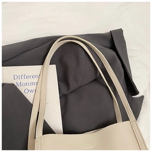 Detail view of cream bucket tote bag showing durable handles and pebble grain texture