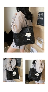 Detail of large black tote bag with snake skin texture and white cloud charm