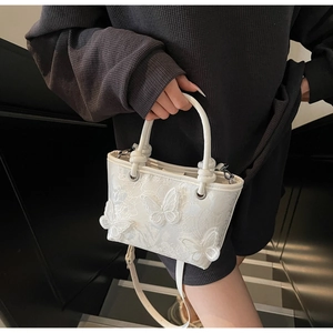 Détail de la broderie de papillon 3D sur un sac seau blanc avec poignée à nœud élégante
