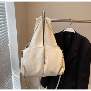 Detail of cream pleated large tote bag with adjustable strap on metal display stand
