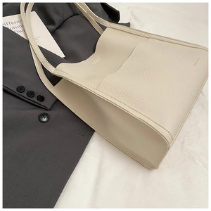 Detail of off-white lychee texture tote bag with front pocket and embossed brand logo