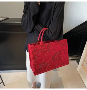 Detail of red floral jacquard tote bag featuring intricate embossed fabric texture