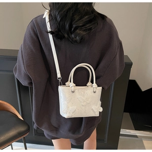 Détails de broderie et papillons 3D sur un sac seau blanc au style élégant et doux