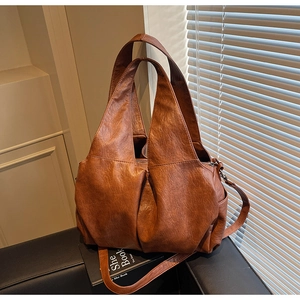 Detail of soft brown PU tote bag with textured folds, side pocket and metal zipper closure