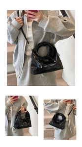Detail der schwarzen glänzenden Handtasche mit Schleifendekor und silbernen Metallteilen