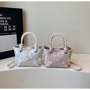 Détail de sacs seaux brodés blanc et rose avec papillons 3D et poignées à nœuds