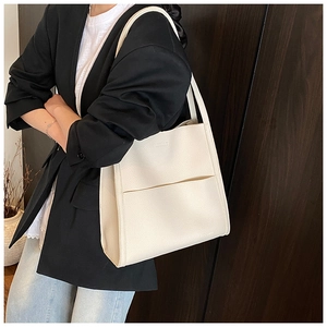 Close-up of off-white lychee grain leather tote bag with minimalist logo detail