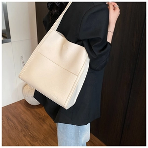Close-up of cream textured leather tote bag with brand logo and functional front pocket
