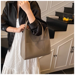 Detail of taupe pebbled leather tote bag with large front pocket and logo branding