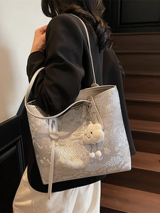 Silver snake pattern tote bag with white cloud plush pendant shown on model