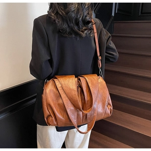 Close-up of a large vintage brown tote bag with natural leather texture and long straps