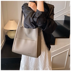 Detail of grey lychee leather tote bag featuring a front pocket and embossed brand logo