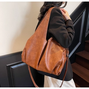 Detail of vintage brown leather tote bag showing wide strap and metallic side zippers