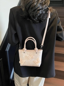 Sac seau rose avec broderie papillon 3D, porté par un mannequin en blazer noir chic