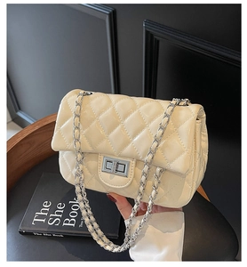 Detailed close-up of beige quilted leather flap bag with silver metal twist lock closure