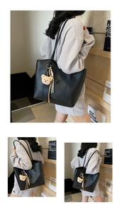 Detail view of black PU leather tote bag with cute bear charm and striped ribbon accessory