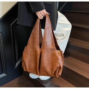 Brown large capacity leather tote bag styled on dark wooden stairs for a classic look