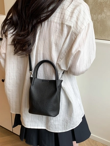 Chic black lychee grain bucket bag for women, worn as a crossbody or top handle purse