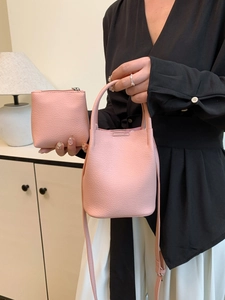 Pink lychee grain leather bucket bag with matching pouch shown in a cozy indoor setting