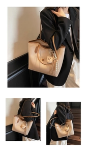 Detail of large beige tote bag with brown trim, cute plush bear charm and striped ribbon