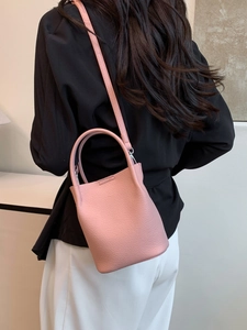 Pink lychee texture bucket bag shown with a minimalist outfit in a clean indoor setting