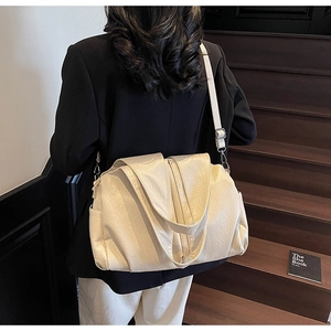 Model view of large cream tote bag paired with black blazer on wooden steps