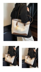 Dettaglio della borsa tote a contrasto con logo WWTU oro, finiture in pelle e charm