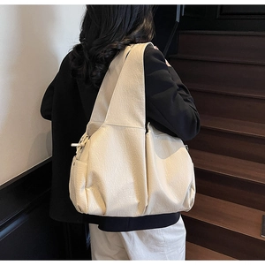 Detail view of large cream shoulder bag with soft textured leather on female model
