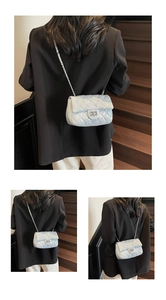 Quilted light blue crossbody bag with silver chain strap and turn-lock on a model
