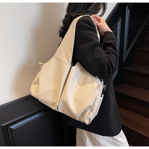 Detailed texture of beige PU leather on a large tote bag with side pocket and stitching