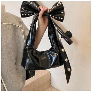 Détail du sac cabas en cuir verni noir avec nœud géant à rivets et design en croissant