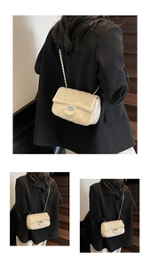 Close-up of quilted cream chain bag showing the square metal lock and crossbody fit