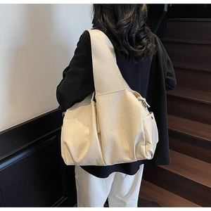 Detail of a large off-white pleated tote bag with a minimalist textured leather finish