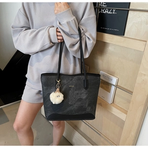 Dettaglio della borsa tote grigia texture marmo con logo oro e ciondolo a forma di pecora