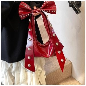 Detailaufnahme der dunkelroten Lackledertasche mit Schleife und silbernen Nieten