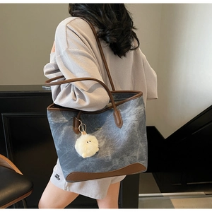 Borsa tote retrò in denim grigio-blu con manici in pelle marrone e ciondolo indossata da modella