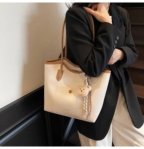 Detail of large beige tote bag featuring brown straps, mini front pocket and silk scarf