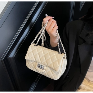 Detail of cream quilted crossbody bag featuring silver metal chain and twist lock closure