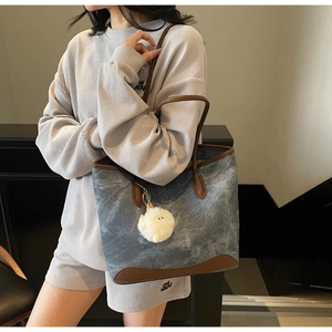 Dettaglio della borsa tote grigio-blu con finiture in pelle marrone e charm peluche