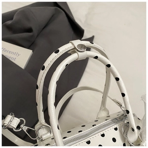 Close-up of black polka dot pattern and silver zipper on white handbag handle