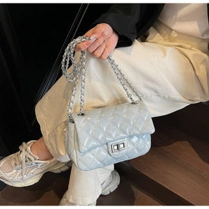 Detail of light blue quilted crossbody bag with silver chain strap and metal lock