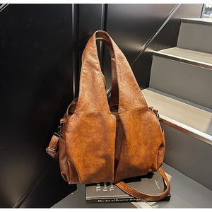 Detailed macro view of caramel leather shoulder bag with vintage texture and pleated design