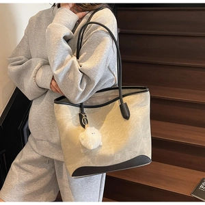 Dettaglio della grande borsa tote a contrasto con trama marmo e ciondolo di peluche