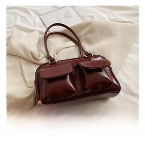 Close-up of a glossy dark red patent leather shoulder bag with two front flap pockets