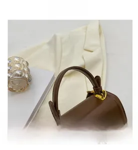 Detail of soft leather handle and gold metal hardware on the brown square handbag