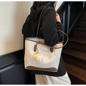 Dettaglio della borsa tote bicolore crema e marrone con ciondolo a gatto in peluche